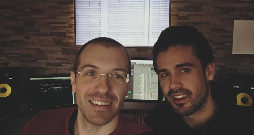 Selfie of Gerard Pastor and Adri Mena with sheet music in the background in a recording studio.