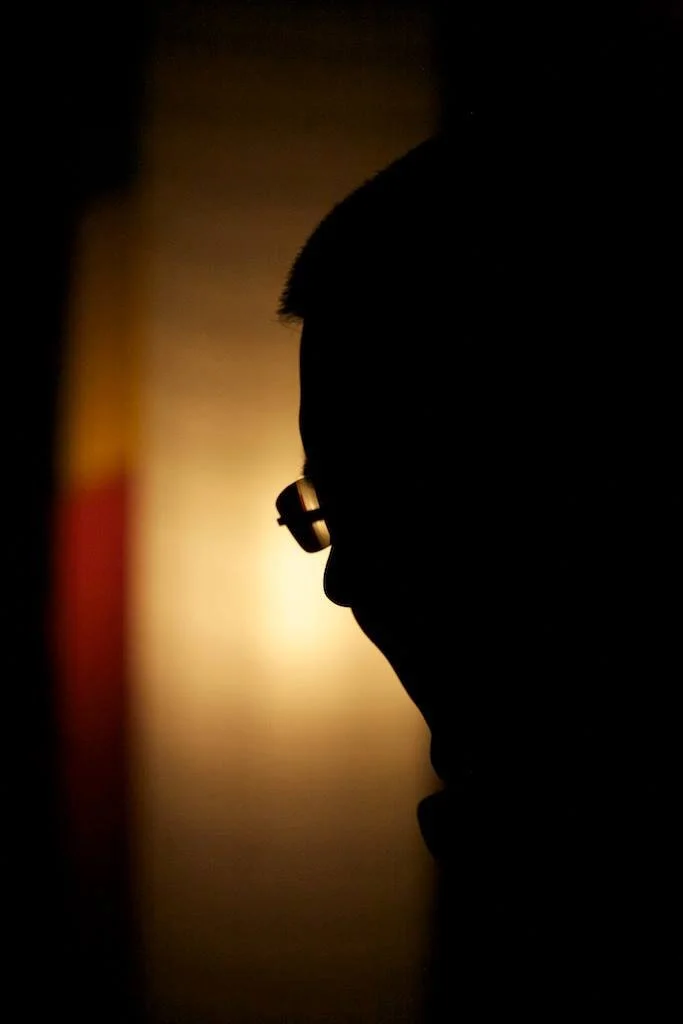 Artistic profile photograph of Gerard Pastor. Only his outline is visible as a shadow, identifiable by his short hair and glasses.