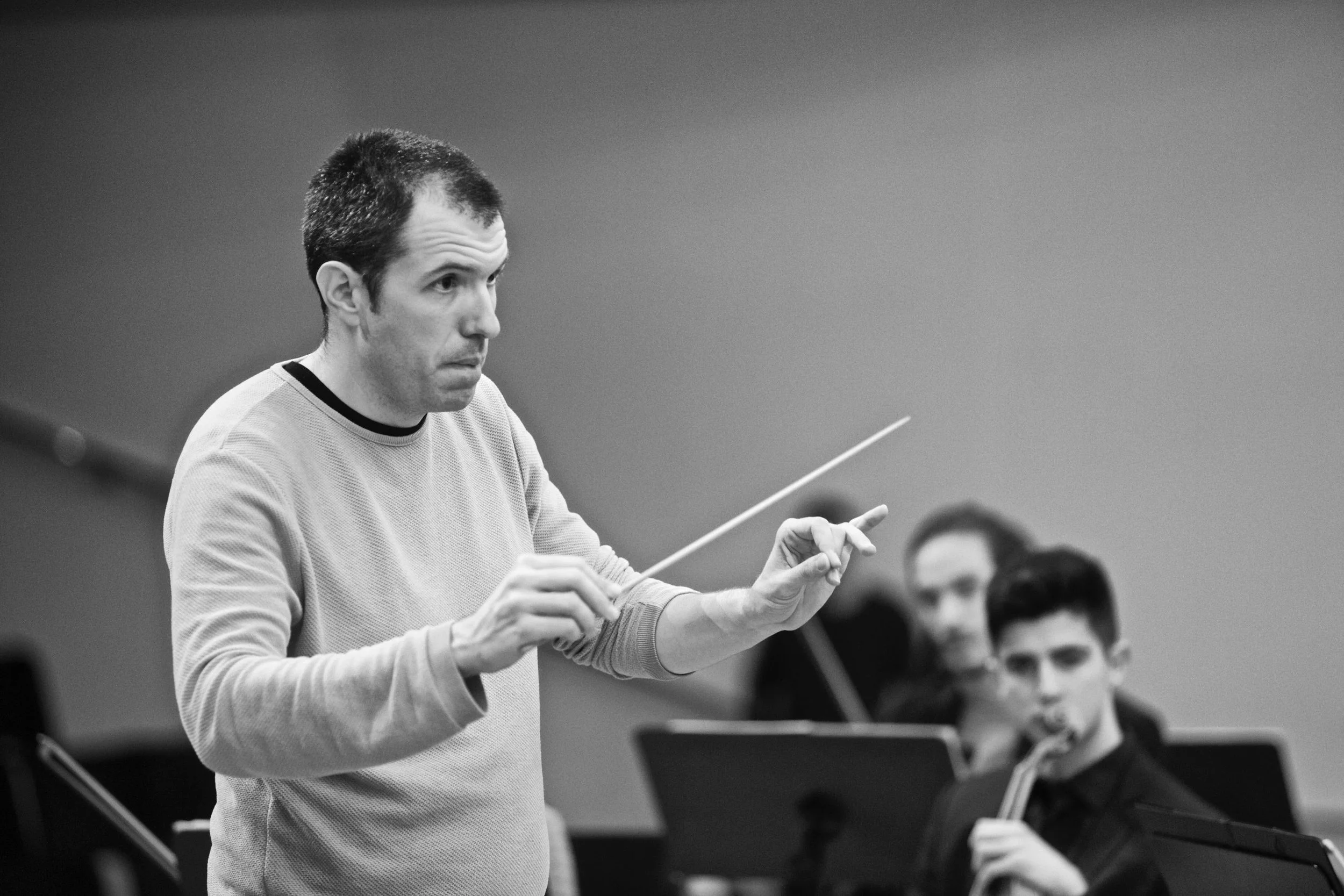 Gerard Pastor conducting a rehearsal of the OFUA youth orchestra. Black and white photograph.